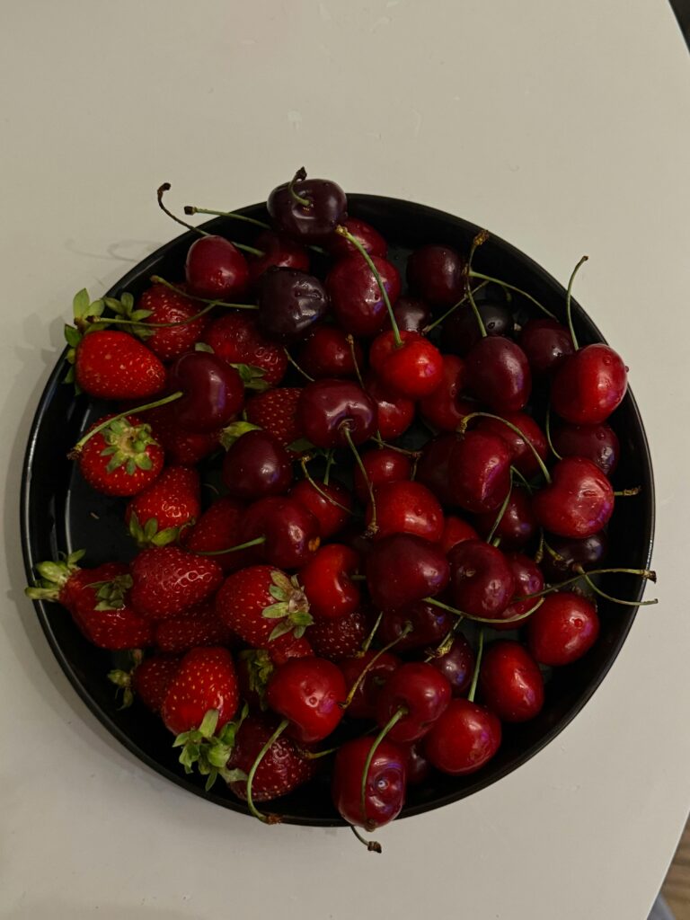 Vibrant strawberries and cherries on a black plate for a refreshing summer treat.